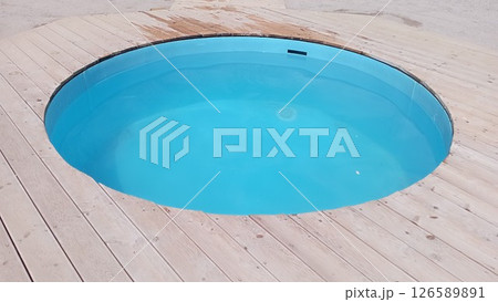 swimming pool with blue water, diagonal lines of wood in the decking details 126589891