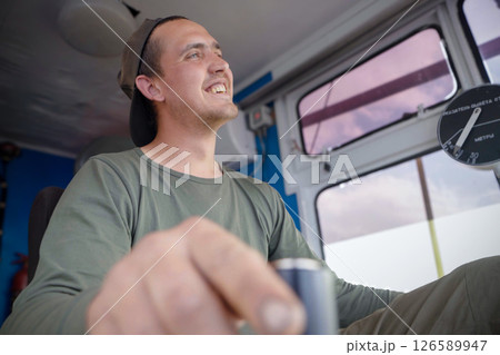 Crane operator actively engaging with joystick in an excavator cab during a sunny workday in the construction site Crane operator actively engaging with joystick in an excavator cab during a sunny workday in the construction site 126589947