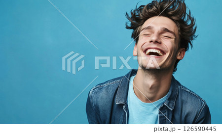 Joyful young man laughing with happiness on vibrant background 126590445