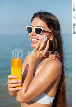 Beautiful Woman in Bikini Applying Sun Cream on Tanned Shoulder. Sun Protection. Skin and Body Care. Girl Using Sunscreen. Portrait Of Female Holding Suntan Lotion or Moisturizing Sunblock. Beautiful Woman in Bikini Applying Sun Cream on Tanned Shoulder. Sun Protection. Skin and Body Care. Girl Using Sunscreen. Portrait Of Female Holding Suntan Lotion or Moisturizing Sunblock. 126590543