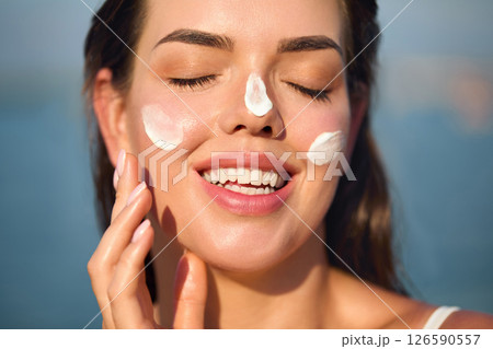 Woman smile applying sun cream on face. Skincare concept. Body Sun protection. sunscreen. Female smear moisturizing lotion on skin. Woman smile applying sun cream on face. Skincare concept. Body Sun protection. sunscreen. Female smear moisturizing lotion on skin. 126590557