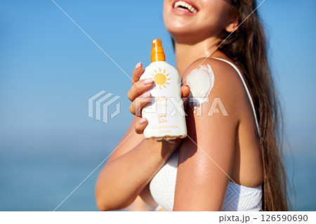Beautiful Woman in Bikini Applying Sun Cream on Tanned Shoulder. Sun Protection. Skin and Body Care. Girl Using Sunscreen. Portrait Of Female Holding Suntan Lotion or Moisturizing Sunblock. Beautiful Woman in Bikini Applying Sun Cream on Tanned Shoulder. Sun Protection. Skin and Body Care. Girl Using Sunscreen. Portrait Of Female Holding Suntan Lotion or Moisturizing Sunblock. 126590690