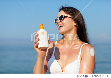 Beautiful Woman in Bikini Applying Sun Cream on Tanned Shoulder. Sun Protection. Skin and Body Care. Girl Using Sunscreen. Portrait Of Female Holding Suntan Lotion or Moisturizing Sunblock. Beautiful Woman in Bikini Applying Sun Cream on Tanned Shoulder. Sun Protection. Skin and Body Care. Girl Using Sunscreen. Portrait Of Female Holding Suntan Lotion or Moisturizing Sunblock. 126590691