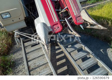 トラックからアユミ板を掛けてコンバインを積み降ろしする 126590879