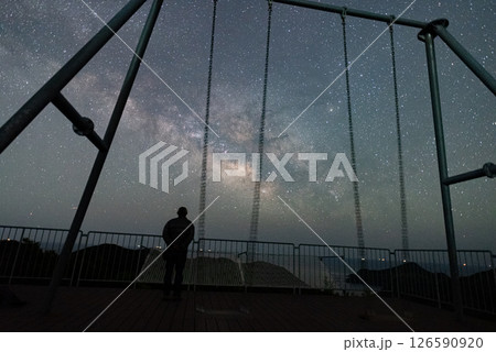 星空を眺める人とブランコのシルエットと美しい天の川 126590920