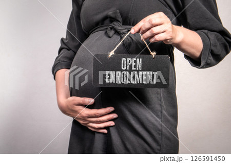 Pregnant Woman Holding Open Enrollment Sign Representing Healthcare Access and Maternity Benefits 126591450