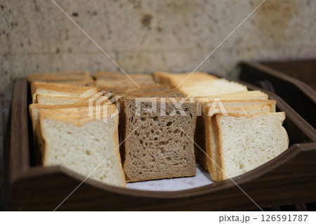 Close-up of sliced white bread and buns in wicker baskets. Perfect for projects related to baking, breakfast, or food service. Warm tones and inviting texture. 126591787