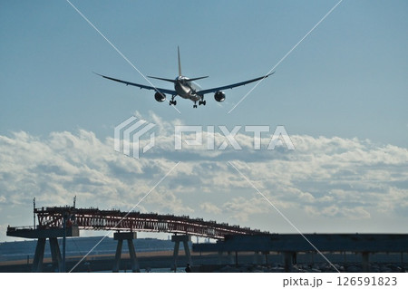 冬晴れの城南島海浜公園から望む羽田空港B滑走路に着陸しようとする旅客機 逆光に機体輝く 冬晴れの城南島海浜公園から望む羽田空港B滑走路に着陸しようとする旅客機 逆光に機体輝く 126591823