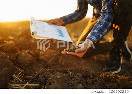 Farm owner checks quality of soil with his hands with tablet and checks fertility before sowing. 126592239