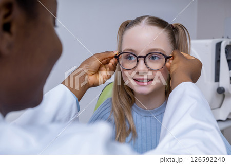Cute caucasian girl trying on new glasses in optometrist office 126592240