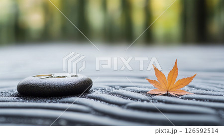 Traditional Japanese Zen garden with raked sand, smooth river stones, and a single maple leaf 126592514