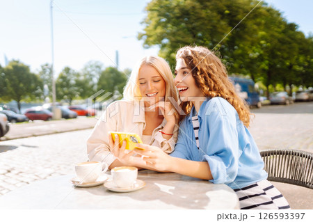 Young women enjoying in coffee and having fun with smartphone. Coffee break after shopping. 126593397