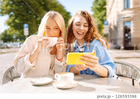 Young women enjoying in coffee and having fun with smartphone. Coffee break after shopping. 126593398