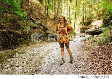 Traveler woman walking along hiking trail through forest thicket in the mountains. Active lifestyle. Traveler woman walking along hiking trail through forest thicket in the mountains. Active lifestyle. 126594141