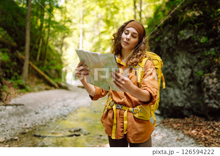 Young woman on a mountain path with a map in her hands, exploring hiking trails. Adventure concept. Young woman on a mountain path with a map in her hands, exploring hiking trails. Adventure concept. 126594222