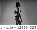 Fit sportswoman in leggings and sports bra looking away and while standing on yellow red 126594325