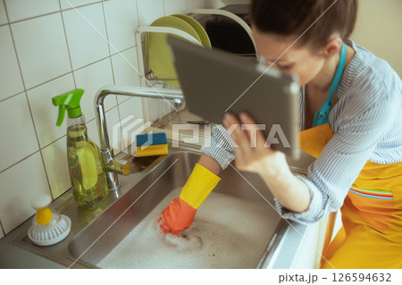 Frustrated homeowner uses tablet near blocked sink Frustrated homeowner uses tablet near blocked sink 126594632