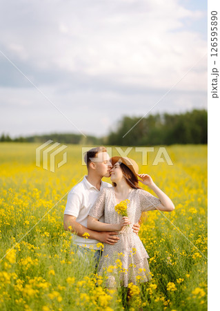 Young couple in love walks through a rapeseed field. The concept of love, test, relationship. Young couple in love walks through a rapeseed field. The concept of love, test, relationship. 126595890