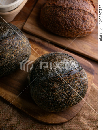 loaf of fresh baked black charcoal sourdough bread. Black ciabatta bread with activated carbon. loaf of fresh baked black charcoal sourdough bread. Black ciabatta bread with activated carbon. 126597575
