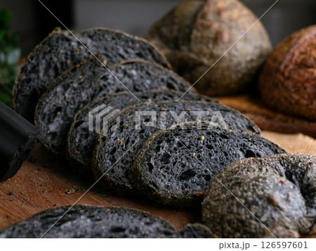 Fresh baked black charcoal sourdough ciabatta bread sliced on wooden board. 126597601