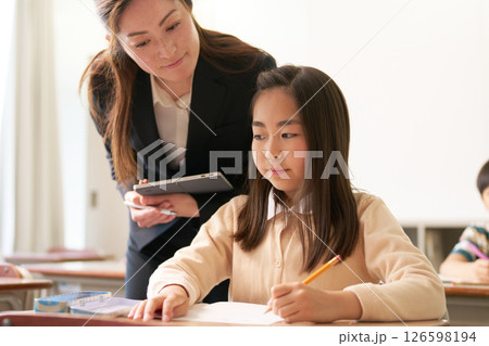 勉強している小学生と見守る先生 勉強している小学生と見守る先生 126598194