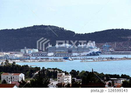 Cruise ship docked at port at dawn with marina and forested hills around Cruise ship docked at port at dawn with marina and forested hills around 126599143