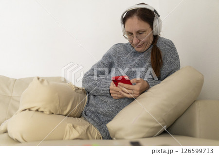 Woman relaxing on sofa using smartphone and wearing headphones 126599713