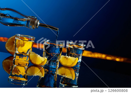 Vodka and lemon slices on a dark blue background. 126600808
