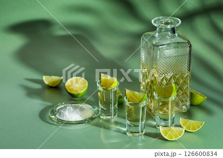 Tequila with salt and lime slices on a green background. 126600834
