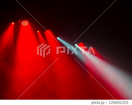 Vibrant dramatic red and white stage light beams cut through hazy darkness creating atmospheric lighting effect for concerts, parties, events, and shows. 126602201