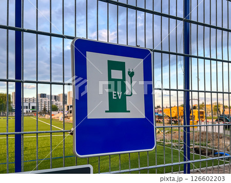Prominent blue and white EV charging sign with green icon and EV text clearly indicates electric vehicle charging station location supporting sustainable urban transportation infrastructure 126602203