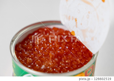 freshly opened tin of red caviar with glossy fish roe filling the container, showcasing its rich texture and vibrant orange color 126602519