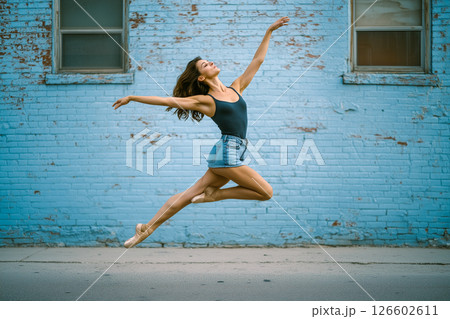 A woman in a blue tank top and blue shorts is doing a pirouette in the air A woman in a blue tank top and blue shorts is doing a pirouette in the air 126602611