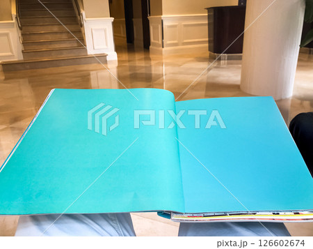 A book placed on a coffee table in the hotel lobby, creating a calm and inviting atmosphere. The soft light and elegant setting emphasize the peaceful and relaxed vibe of the space. 126602674