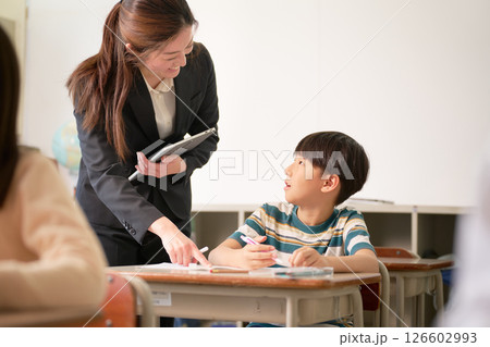 勉強中の小学生と笑顔で指導する先生 126602993