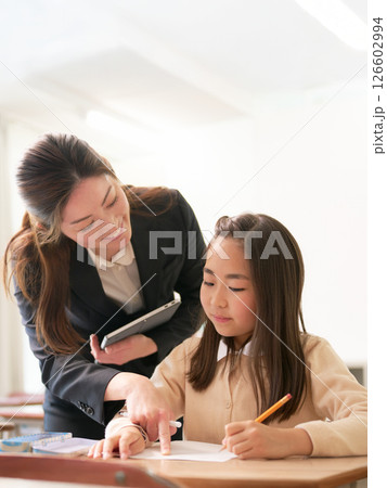 勉強中の小学生と指導する先生 勉強中の小学生と指導する先生 126602994