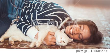 Funny girl hugs her white fluffy cat at home. 126603433
