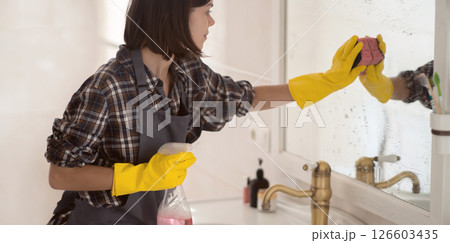 Young woman is washing mirror in the bathrom. 126603435