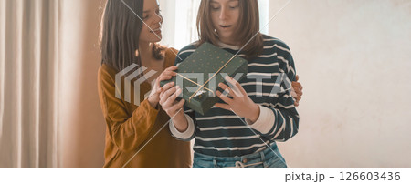 Two happy girls celebrate holiday, making nice gifts. 126603436