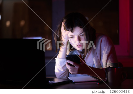 Girl works on a laptop at home at night. Girl works on a laptop at home at night. 126603438