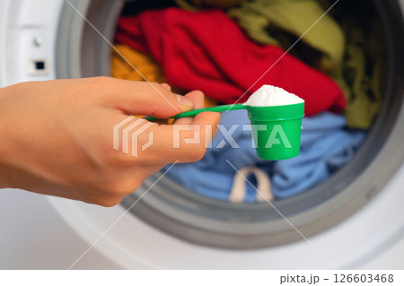 Female hand holds a cap with washing powder. 126603468