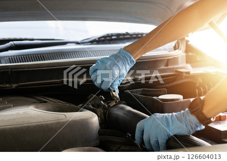 The mechanic is fixing the engine, using a wrench to tighten the nuts. 126604013