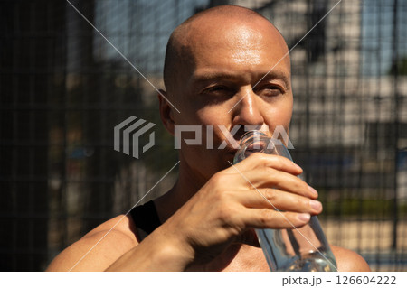 Athletes handsome man drinking water on outdoor sports ground. Water balance for active workout. Heat summer. Close up. Athletes handsome man drinking water on outdoor sports ground. Water balance for active workout. Heat summer. Close up. 126604222