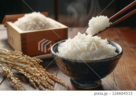 稲穂とごはん茶碗に盛られた湯気の立ち上る白米を箸で持ち上げるシーン。日本の和食イメージ 126604515