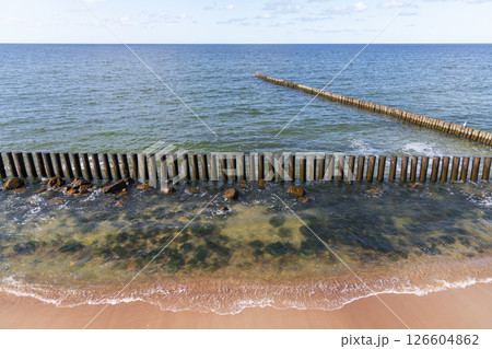 A scenic view of a wooden breakwater extending into the calm sea 126604862