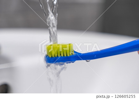 Brushing teeth with running water from a faucet for effective dental hygiene and daily oral care routine Brushing teeth with running water from a faucet for effective dental hygiene and daily oral care routine 126605255