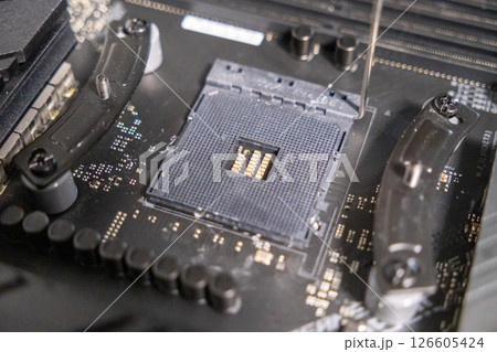 cpu socket on a motherboard with visible pins and fastening brackets during computer assembly process, close-up detail of electronic components cpu socket on a motherboard with visible pins and fastening brackets during computer assembly process, close-up detail of electronic components 126605424