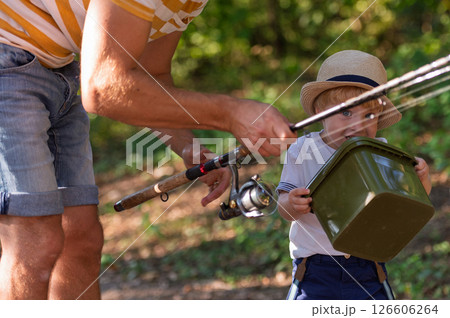 Father and little son walking together in nature on a fishing trip Father and little son walking together in nature on a fishing trip 126606264