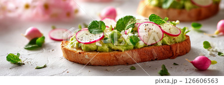 Enjoying a vibrant spring breakfast with creamy avocado spread on toasted bread, garnished with thinly sliced radishes and fresh mint leaves for added flavor, banner Enjoying a vibrant spring breakfast with creamy avocado spread on toasted bread, garnished with thinly sliced radishes and fresh mint leaves for added flavor, banner 126606563