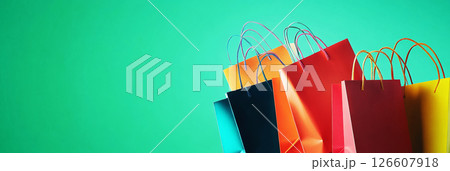 A vibrant stack of colorful shopping bags on a green background, exuding a modern and stylish vibe, ideal for promoting retail and fashion in banners, flyers, or advertisements, banner 126607918